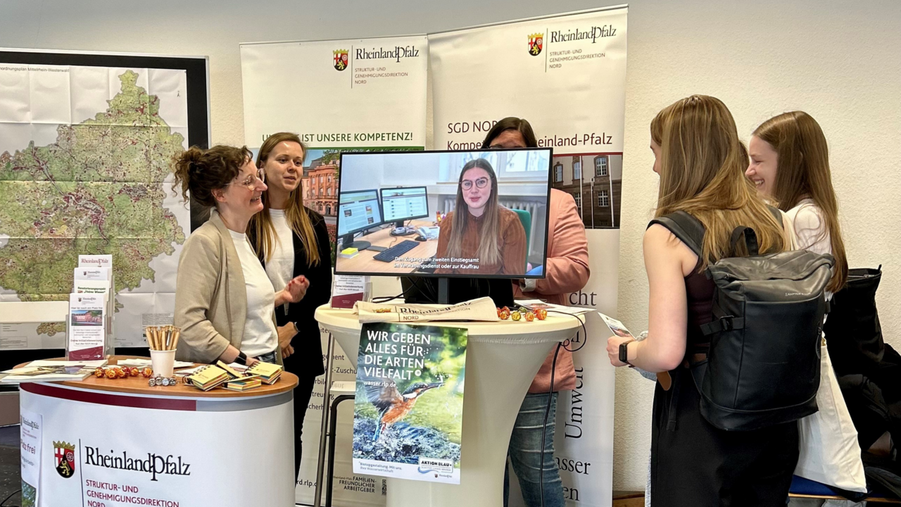 Messestand mit fünf Personen und Bildschirm