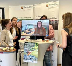 Messestand mit fünf Personen und Bildschirm