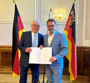 SGD-Nord-Präsident und Beliehener halten Urkunde in die Kamera.