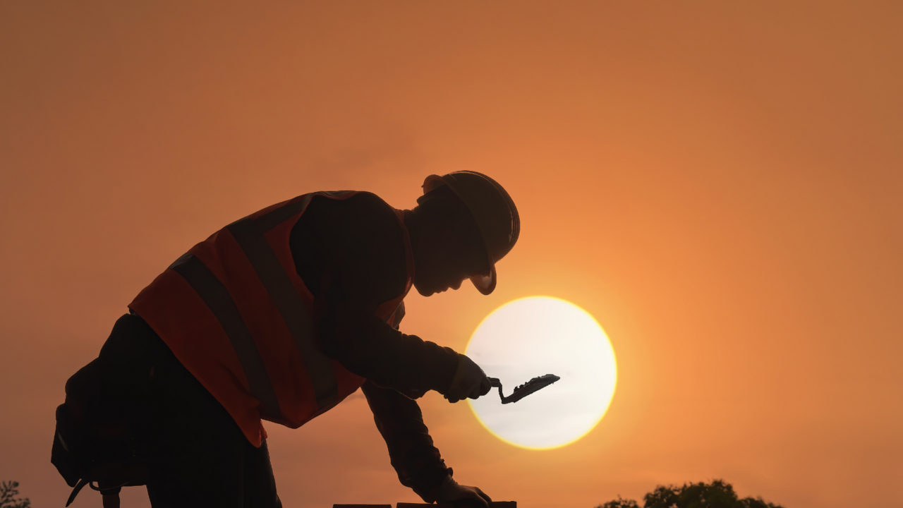 Silhouette eines Bauarbeiters vor Sonnenauf- oder untergang