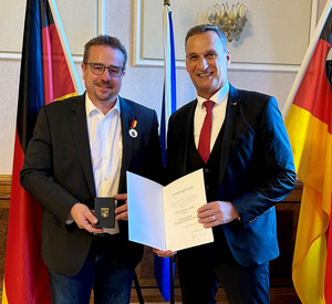 SGD-Nord-Präsident und Beliehener halten Urkunde in die Kamera