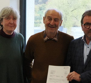 Eine Frau und zwei Männer mit einem Bescheid