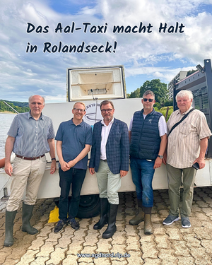 Personengruppe steht vor Aal-Transportwagen