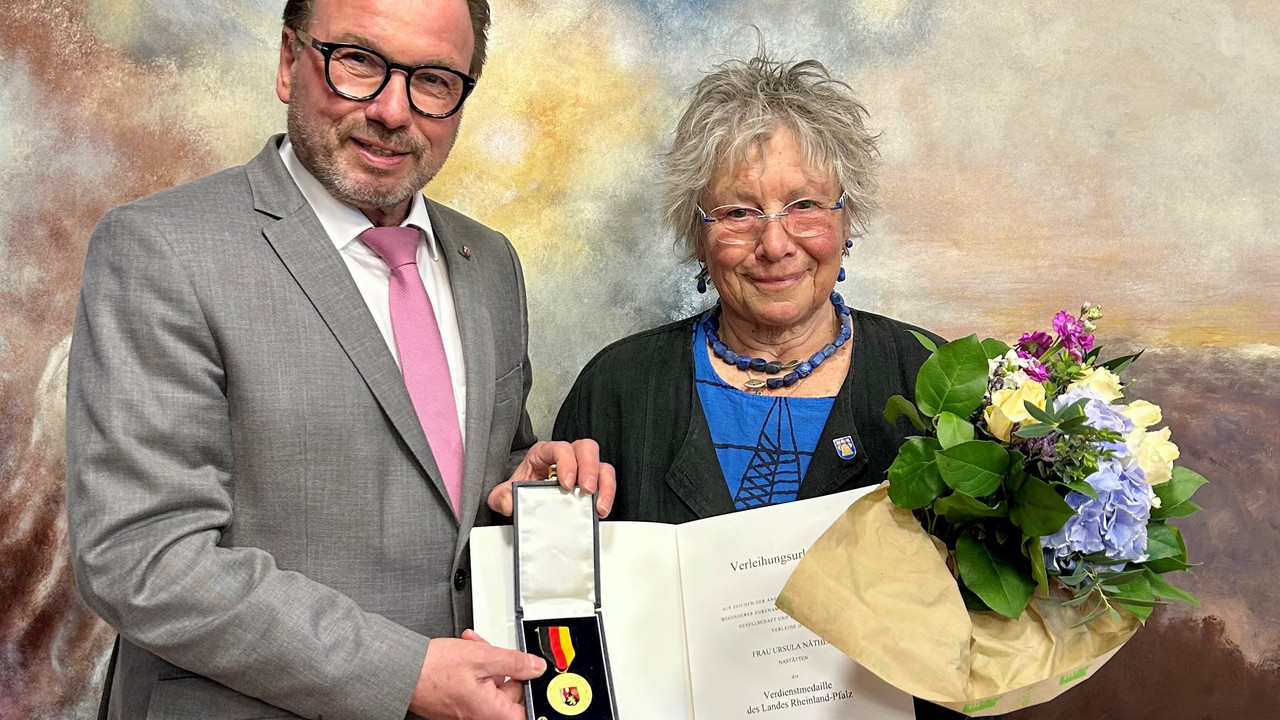 Zwei Personen mit Urkunde und Blumenstrauß