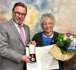 Zwei Personen mit Urkunde und Blumenstrauß